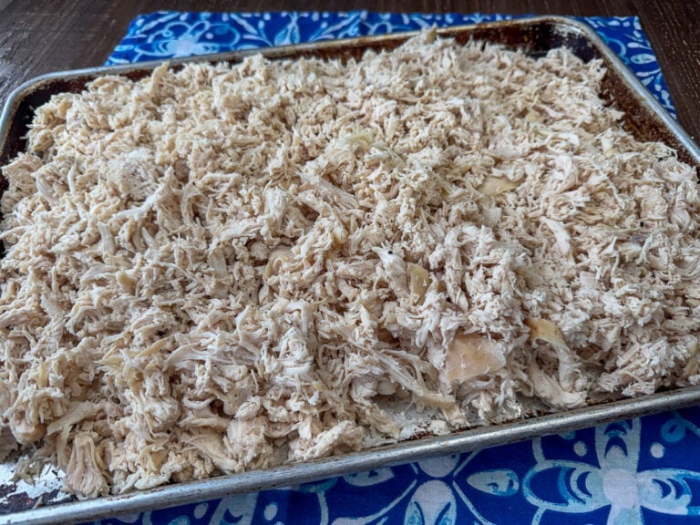 Side view of baking sheet heaped up with an easy recipe for shredded chicken.