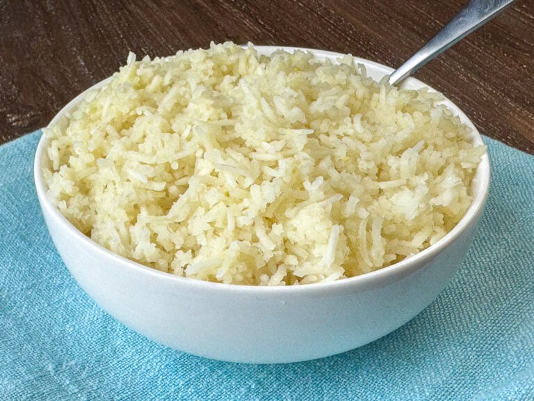 Side view of a bowl of tender and fluffy white rice made to serve 50 people, resting on a teal napkin.