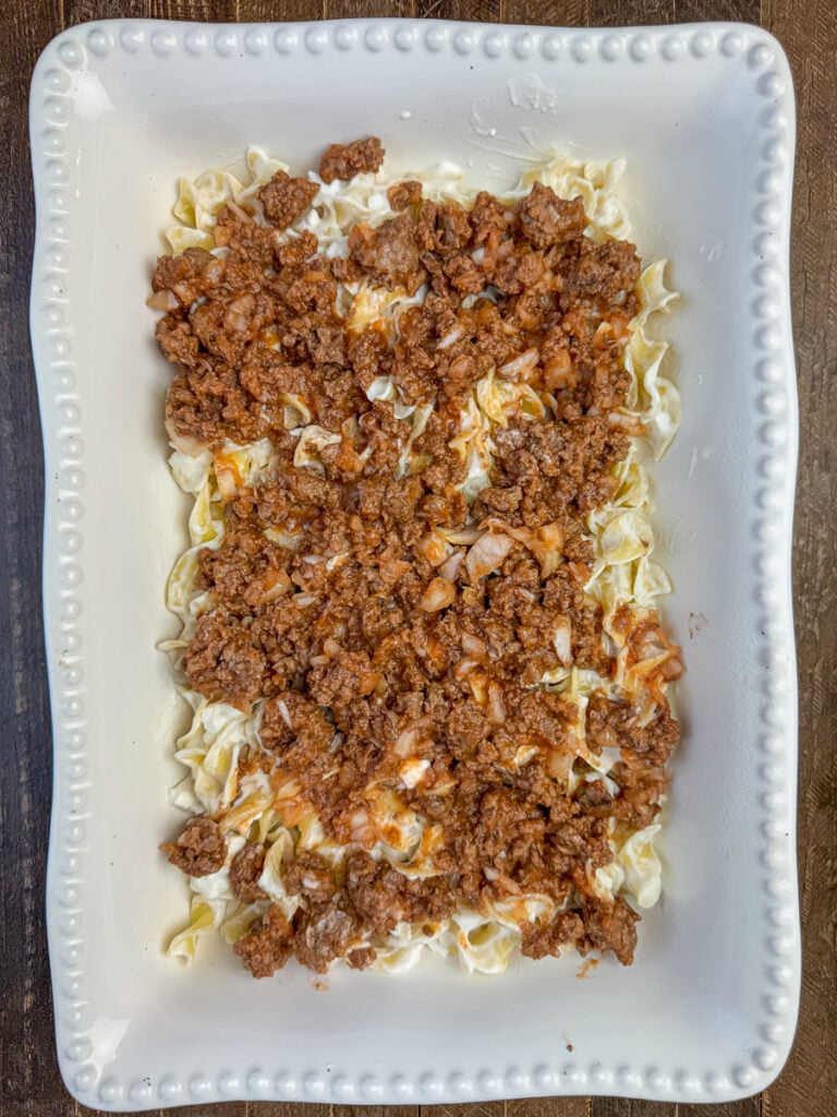 Half a pound of saucy hamburger spread over sour cream coated noodles in a casserole dish.