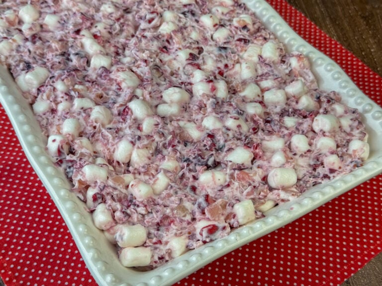 Side view of a big batch of cranberry marshmallow fluff salad in a white 9 x 13" dish on a red napkin.