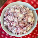 Mini marshmallows in a bowl of fresh cranberry salad on a red and white napkin.