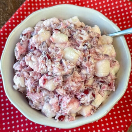 Mini marshmallows in a bowl of fresh cranberry salad on a red and white napkin.