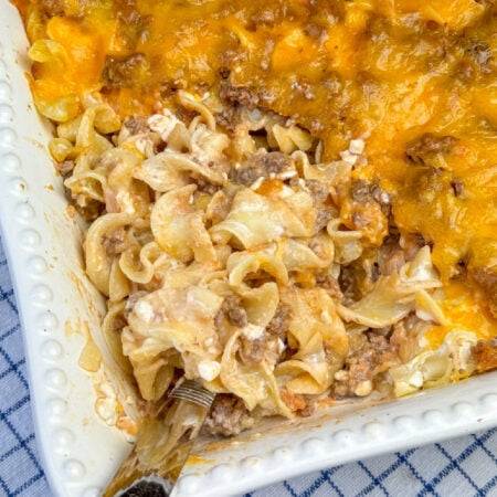 Serving spoon ready to scoop a hearty Sour Cream Noodle Bake out of the full dish.