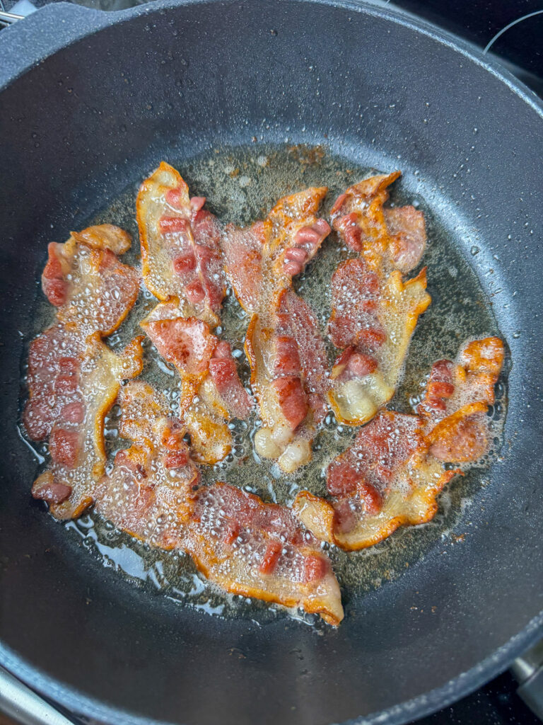 Bacon frying in a skillet.