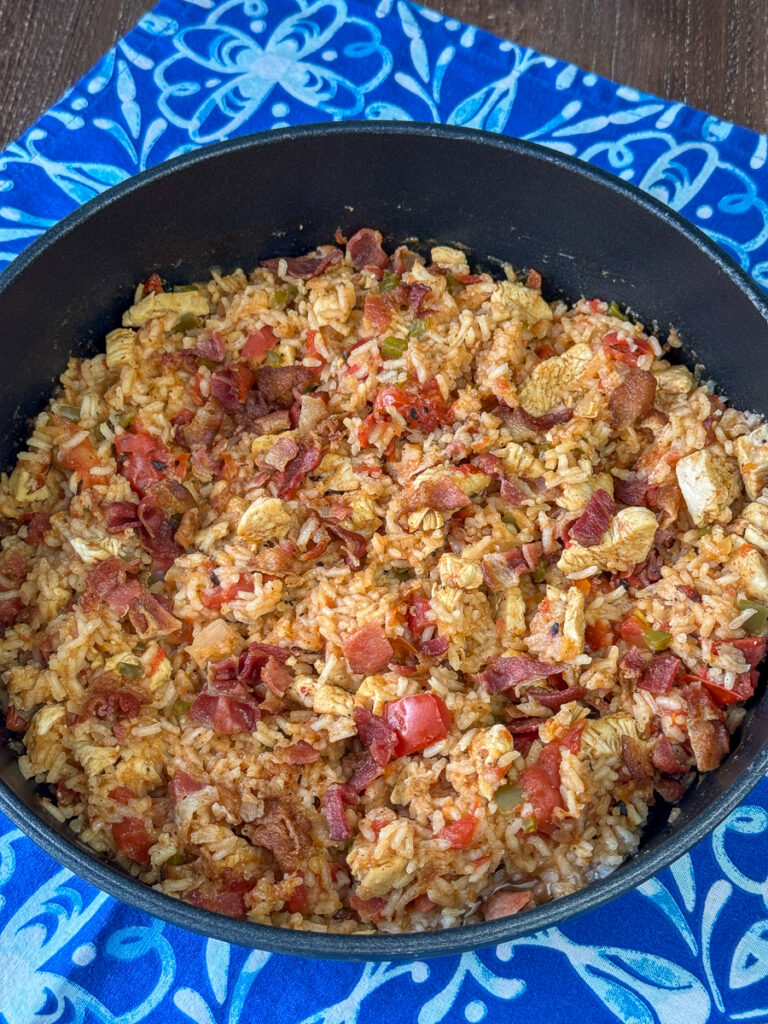 Overhead view of a skillet filled with chicken and rice with plenty of bacon stirred in for a savory flavor.